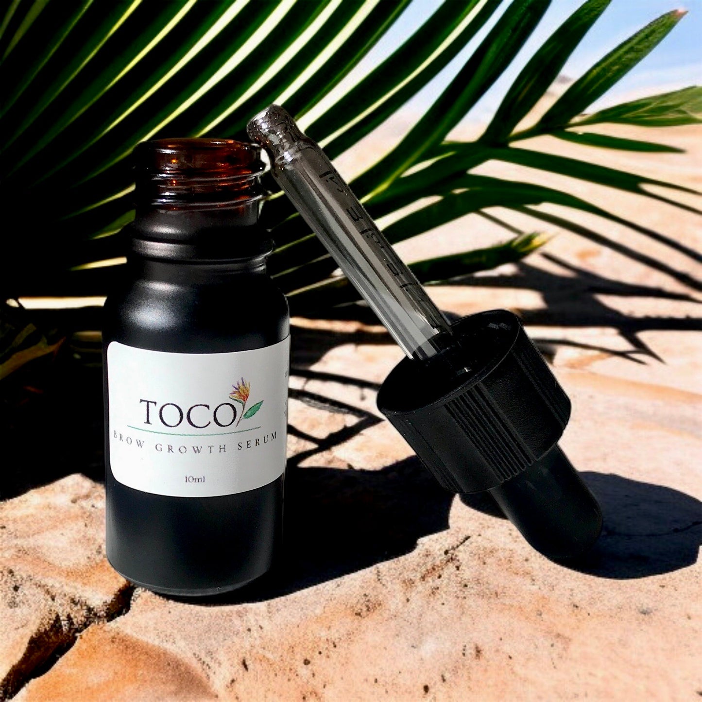 10ml glass bottle of brow growth serum with dropper poolside