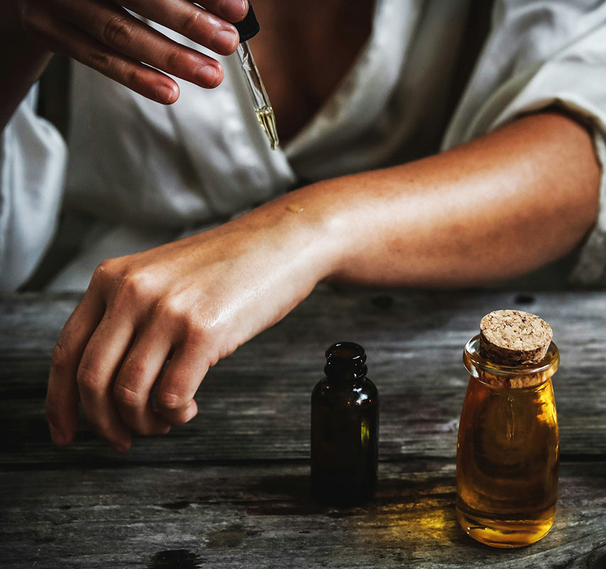 woman putting dropper of oil on her arm