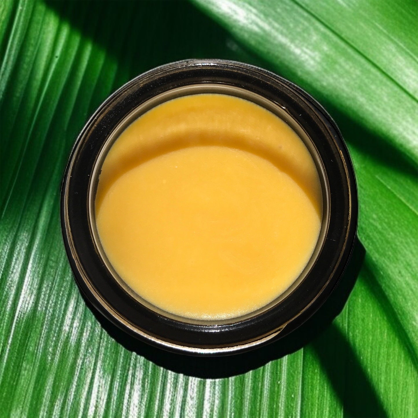 close-up of hibiscus glow balm in black glass jar