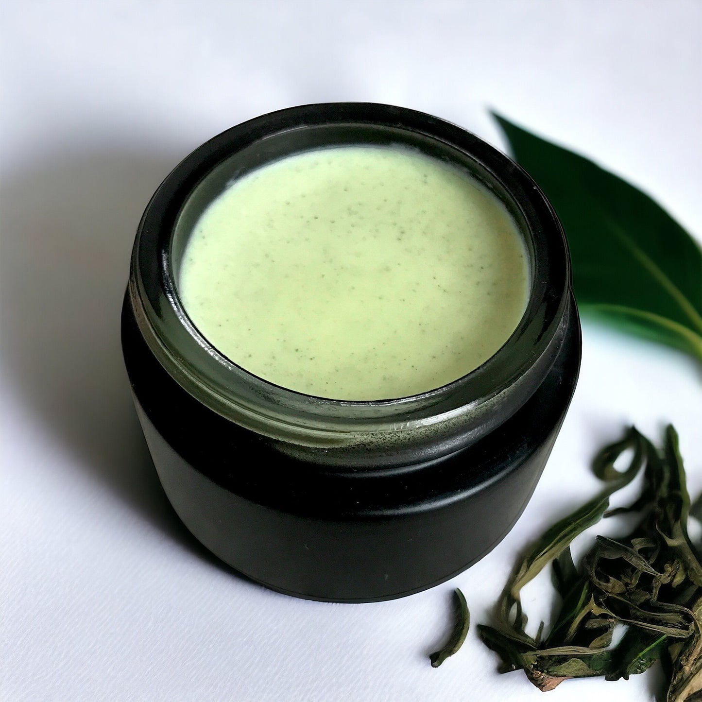 Matcha Clear Skin Balm on a white background with tea leaves