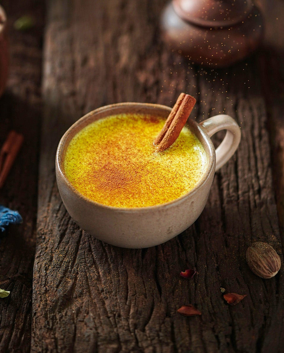 cup of golden milk and cinnamon stick