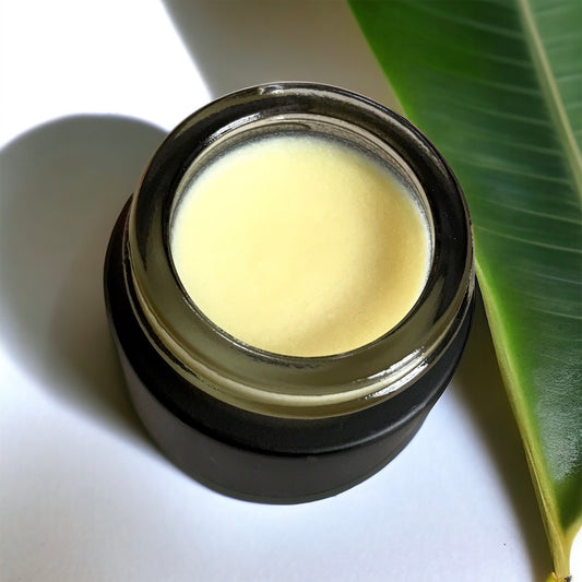 Black container with banana eye concentrate next to a green leaf on a white background