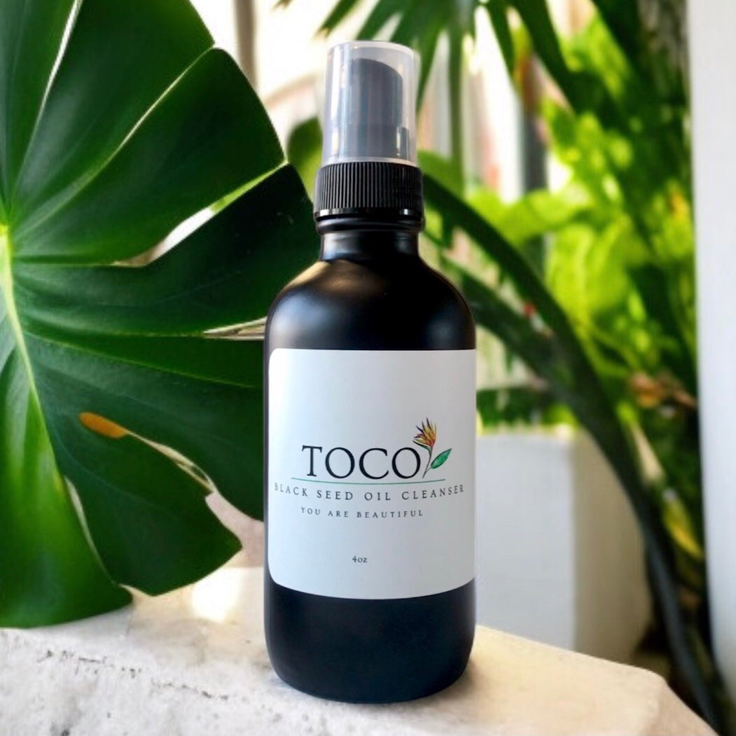 Bottle of Toco Black Seed Oil Cleanser with green leaves in the background