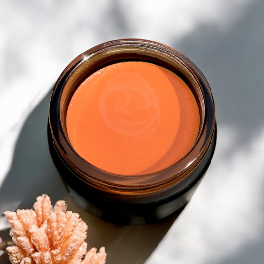 Jar of Hibiscus Glow Balm with coral on a light background