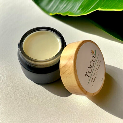 Banana Eye Concentrate in black jar with a green leaf in background