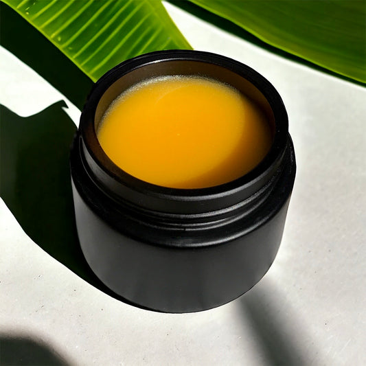 close-up of hibiscus glow balm in a black glass jar in sunlight