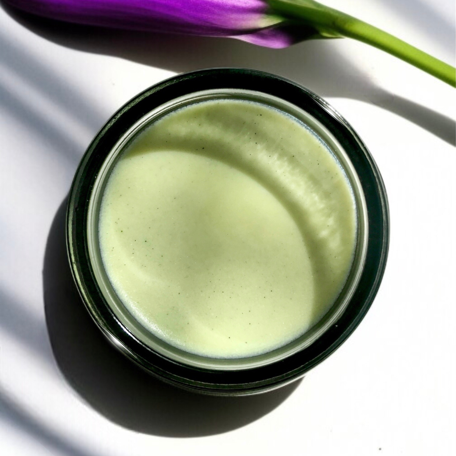 Jar of matcha clear skin balm with a purple flower on a white background