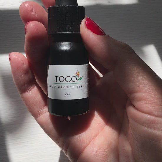 10ml black glass dropper bottle of brow growth serum being poured into hand in sunlight 