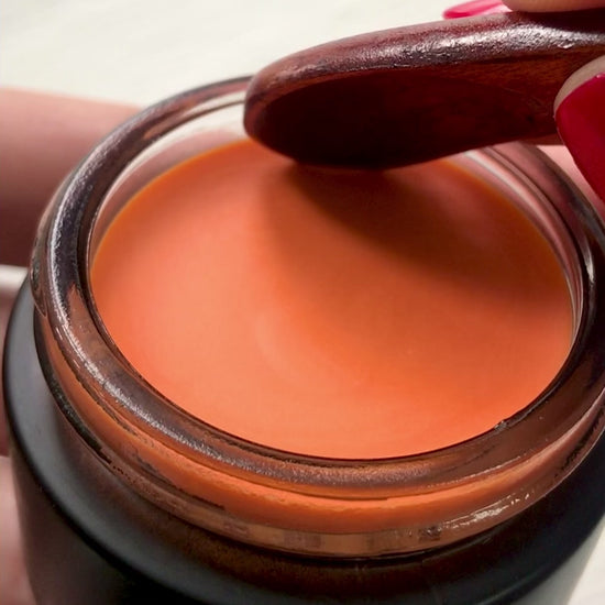 Scooping Hibiscus glow balm with wooden spoon